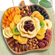 Fruta seca y nueces en bandeja de servir de tabla de cortar de bambú con forma de manzana