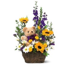 Cesta de flores de primavera y un oso de peluche